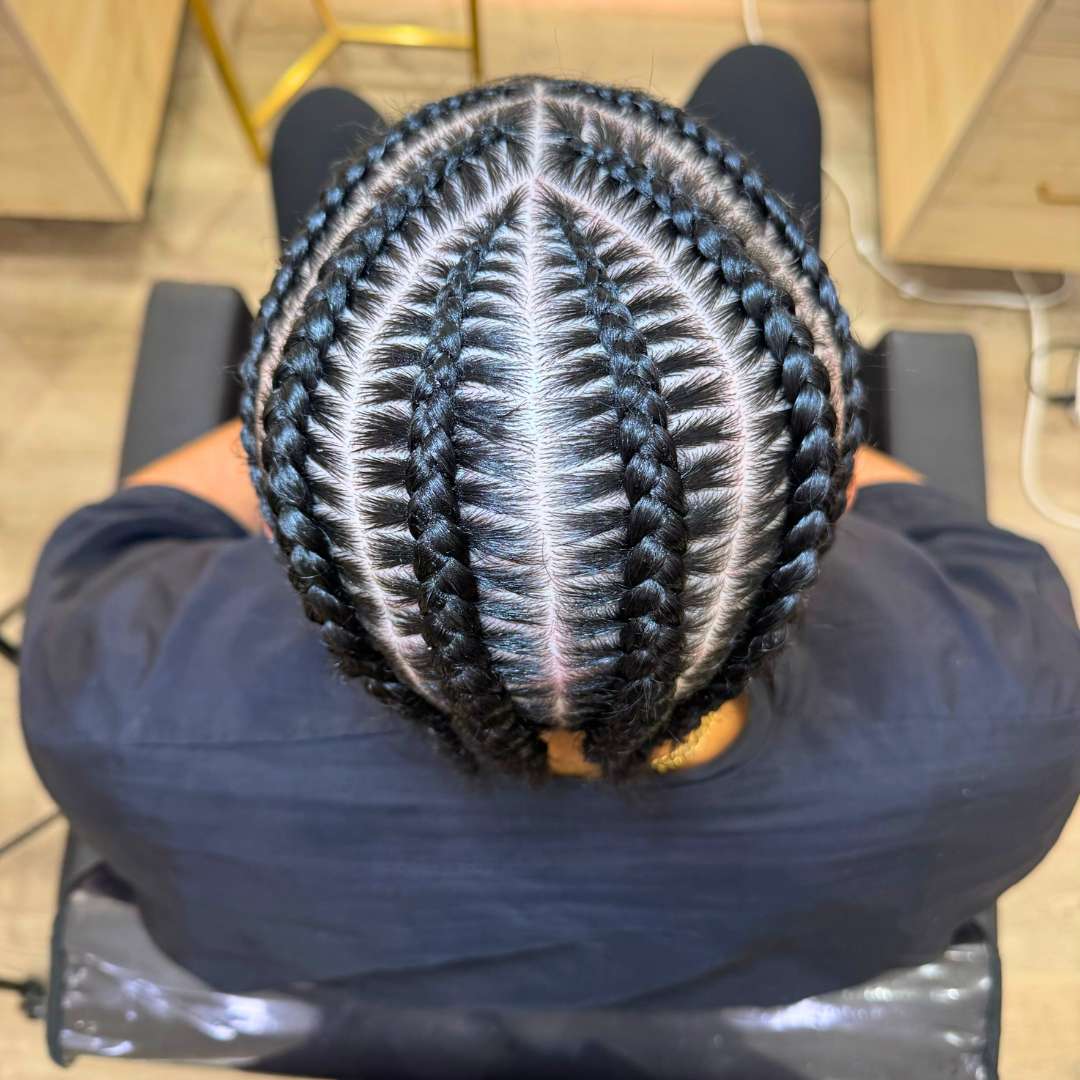 Detail of protective spring twists extensions in progress, showing hands sectioning natural hair for styling.