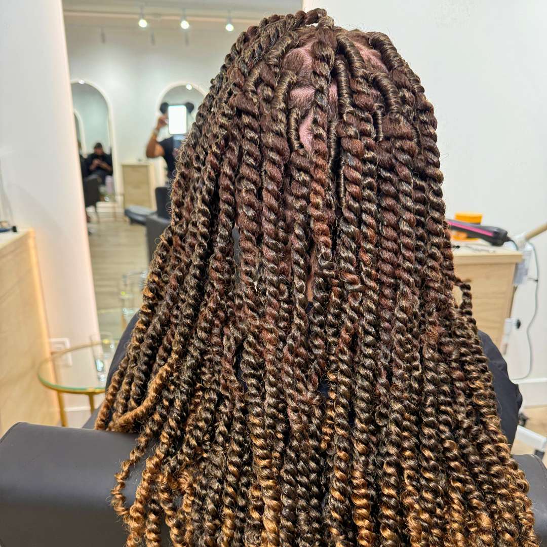 Client seated in salon showcasing long braided protective style cornrows by Des Curl Spa’s stylists