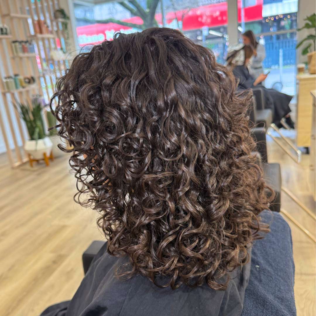 Hair stylist using diffuser to dry and define curls
