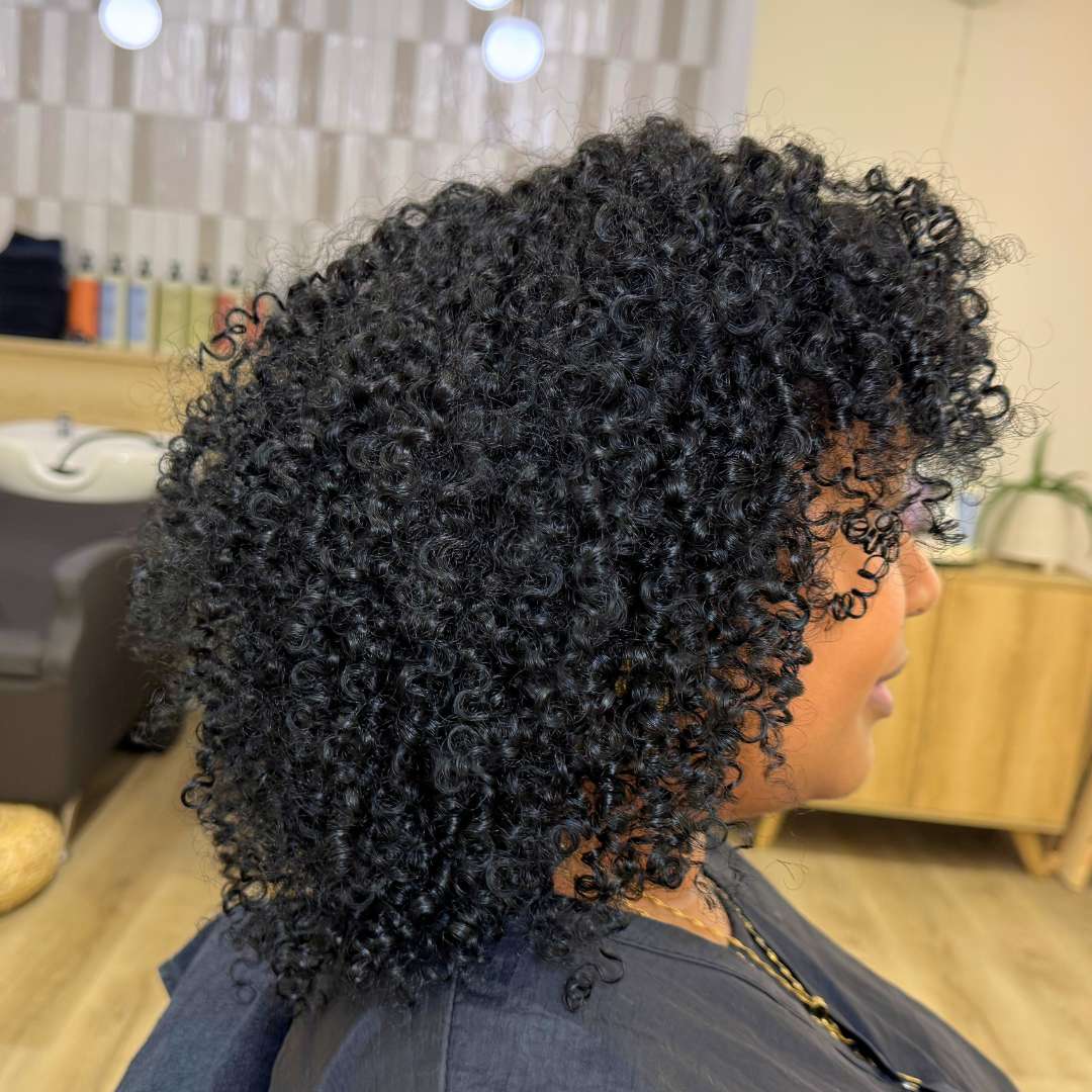 Client under hooded dryer during curl-setting process