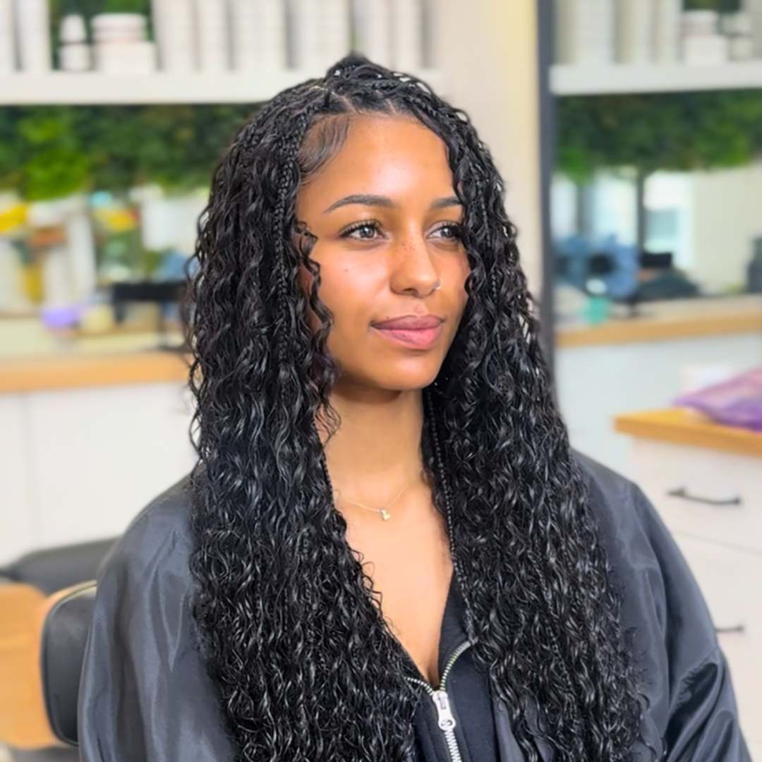 Model wearing long flowing box braids in a protective hairstyle, styled to preserve curl health and growth.