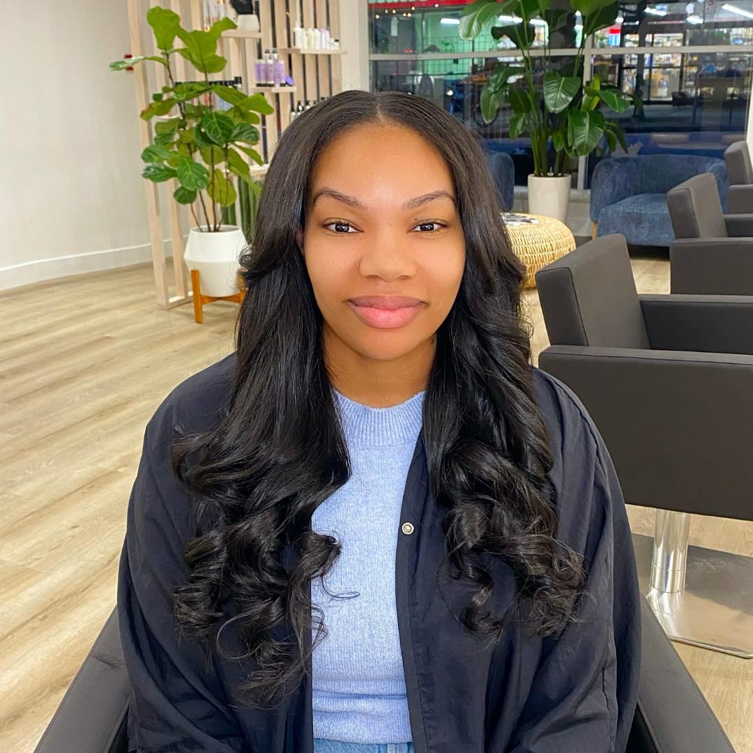 A woman with long sits in a salon, focusing on restoring damaged hair and promoting healthy growth.