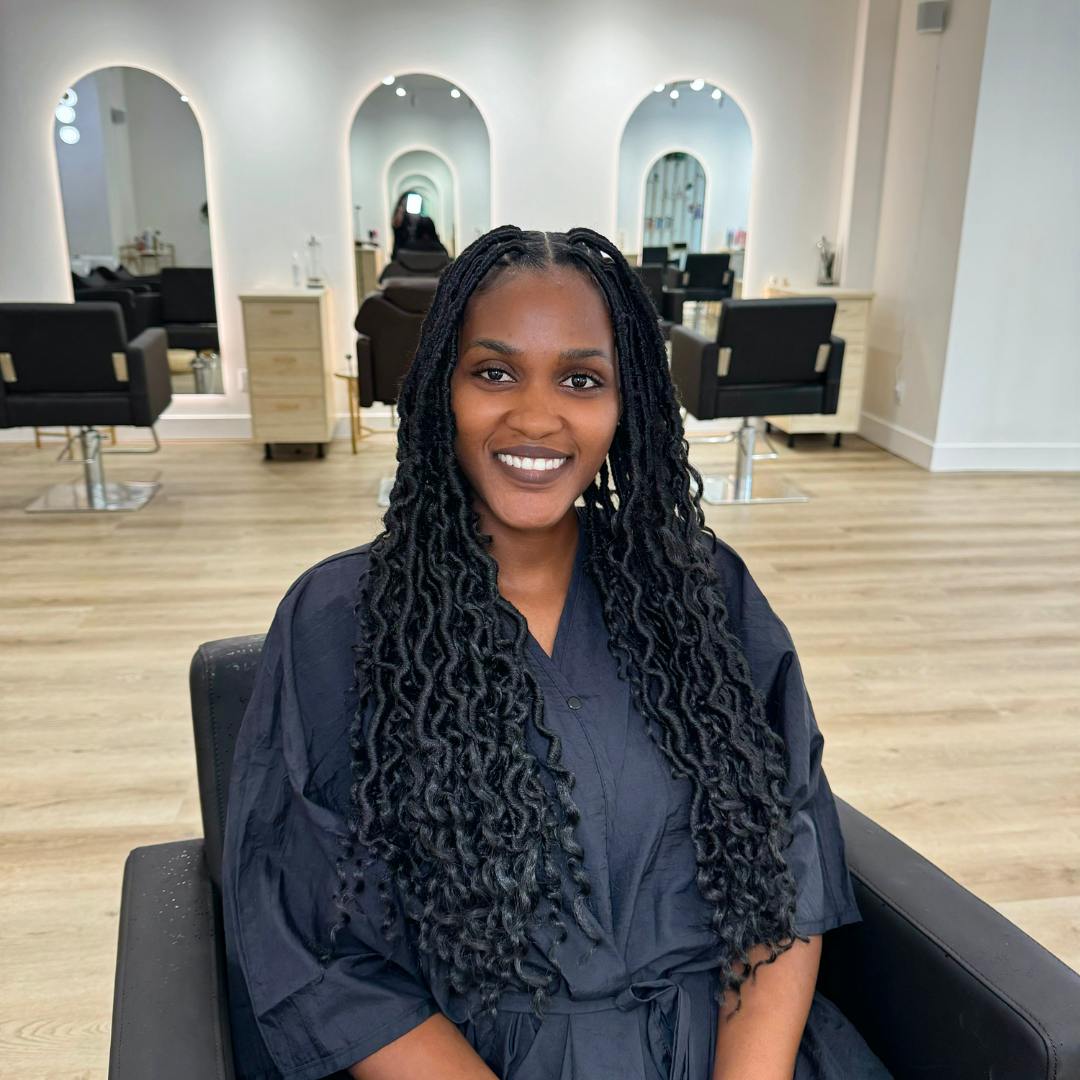 A woman with long  hair sits in a salon, Showing her curly hair style