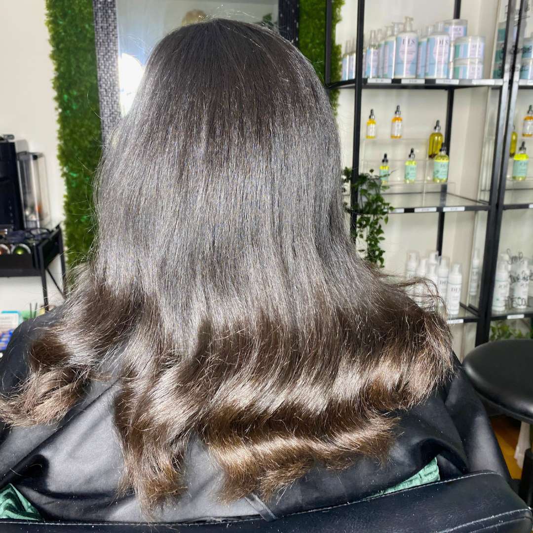 Stylist installing luxury tape-in extensions for curly hair